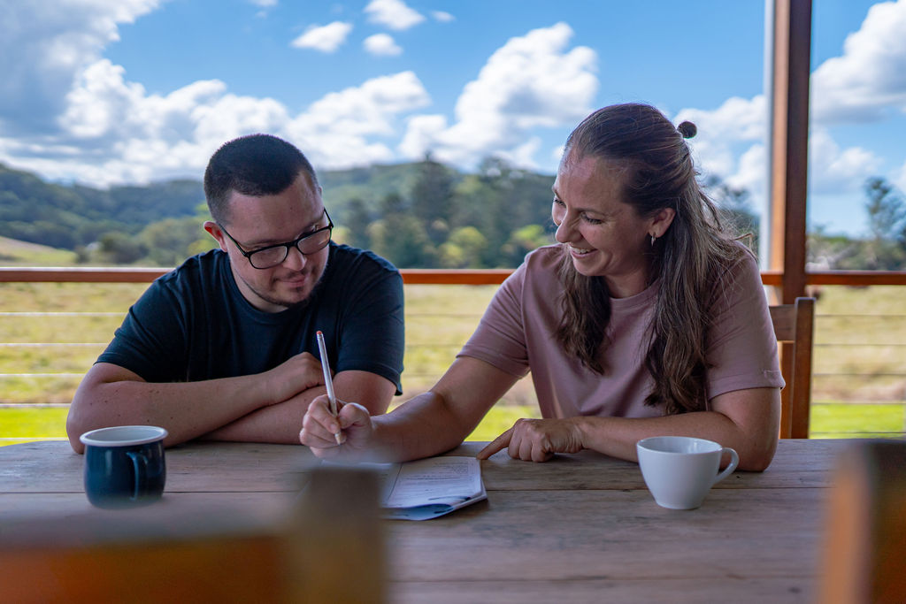 Support coordinator working with a person with disability, both smiling at a laptop